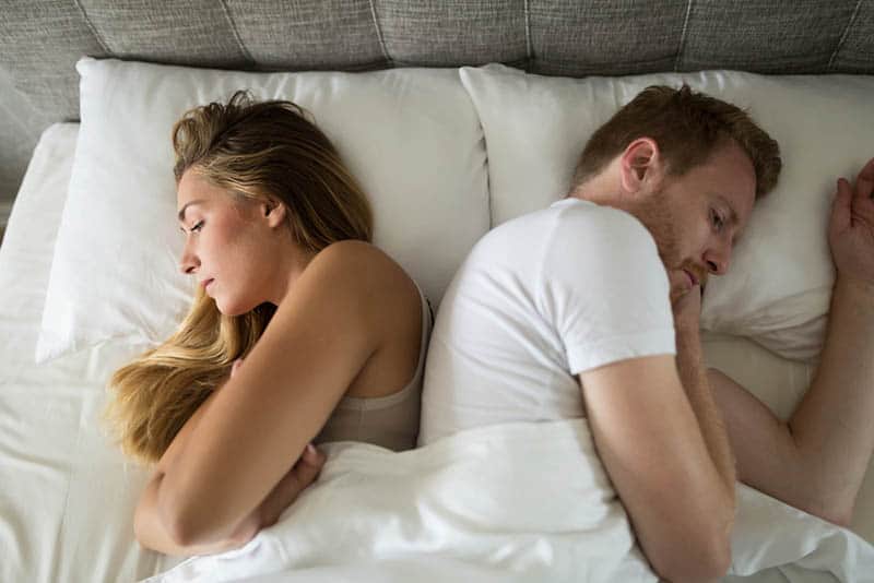 Couple malheureux allongé sur le lit dos à dos