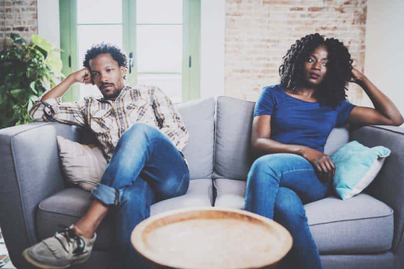 Des hommes se disputent avec sa petite amie, qui est assise à côté de lui sur le canapé