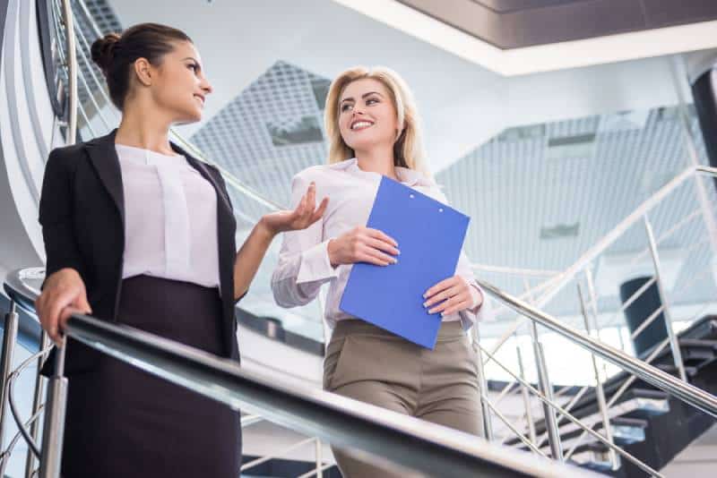 Deux femmes d'affaires séduisantes descendent les escaliers et discutent.