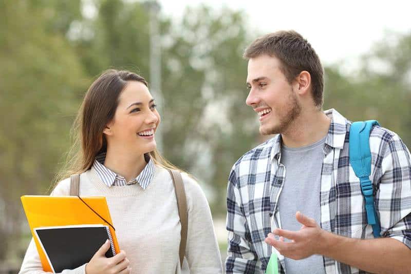 Deux étudiants souriants discutent à l'extérieur