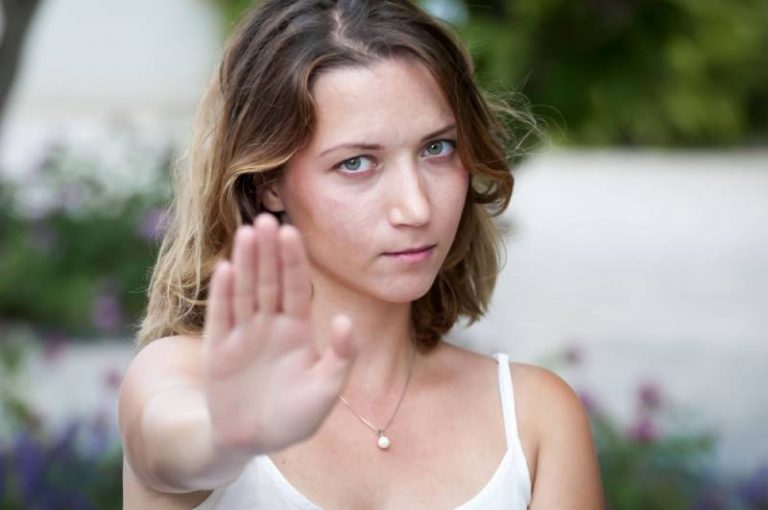 Une jolie fille blonde de type caucasien dit NON, donne un signe pour arrêter