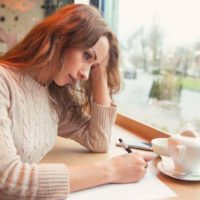 Une jeune femme triste écrit une lettre avec un cœur brisé et se sentant désespérée