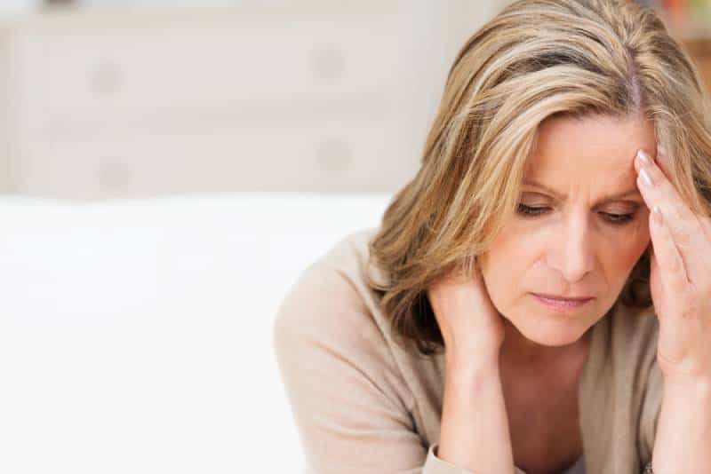 Femme souffrant de stress ou d'un mal de tête grimaçant de douleur en se tenant la nuque