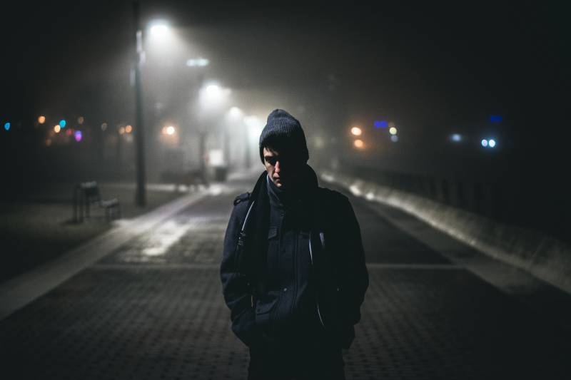 Homme se tenant près des lampadaires pendant la nuit