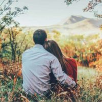 Un couple s'embrasse et s'assoit tout près dans la forêt