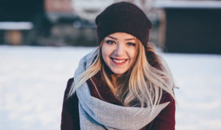 une femme blonde avec un chapeau sur la tete rit