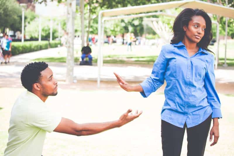 Portrait d'une jeune femme montrant un geste de la main à un homme désespéré dans l'espoir de la persuader de voir son point de vue.