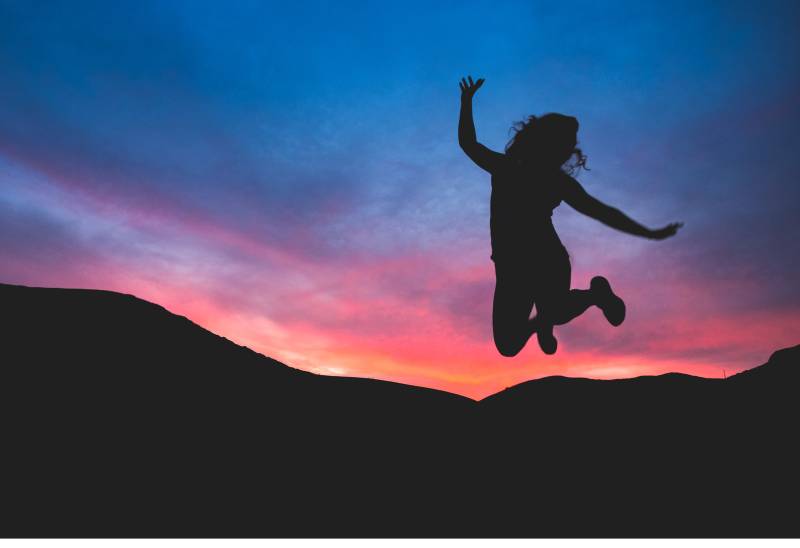 Silhouette de la personne qui saute à l'aube
