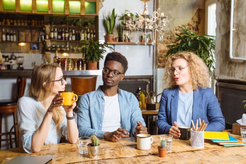 Un Africain sérieux et concentré et deux femmes au café, en train de discuter