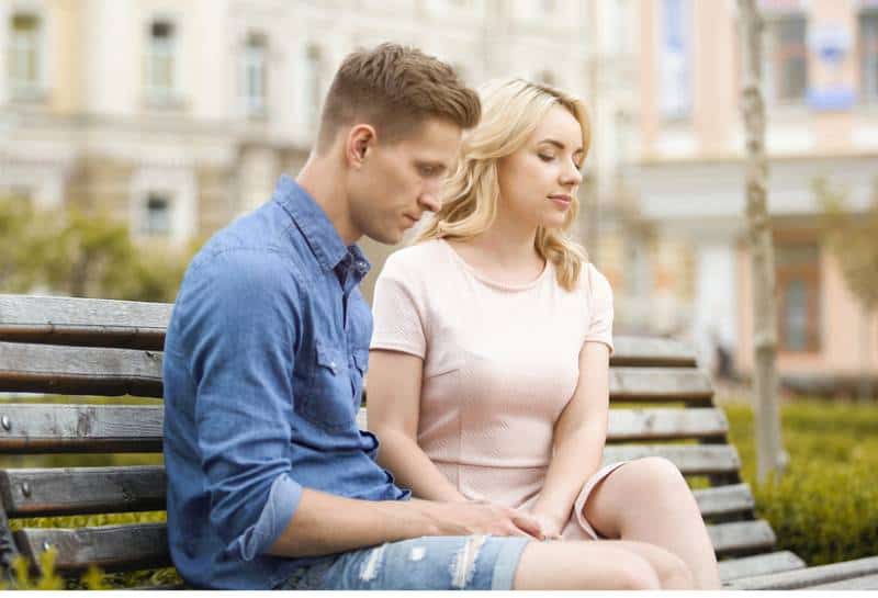 Un couple se sentant mal à l'aise alors qu'il est assis sur un banc en silence