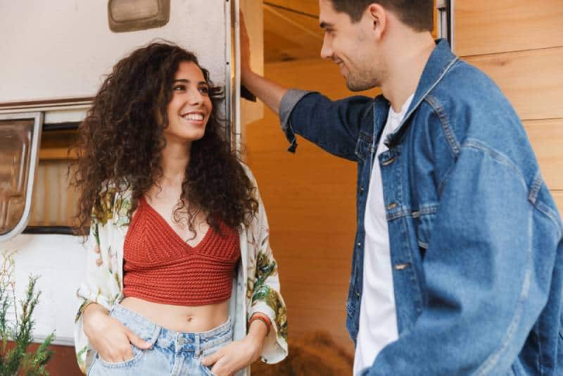 Un couple souriant parle en se tenant près de la maison