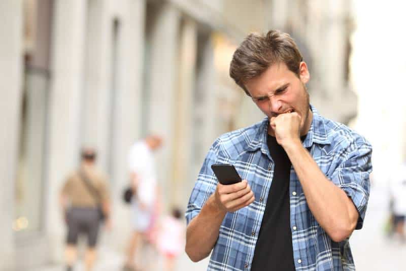 Un homme en colère regarde le téléphone