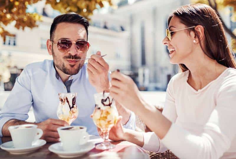 Un homme et une femme heureux en mangeant une glace au café