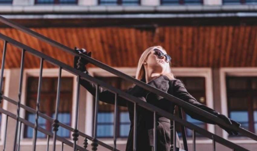 une femme avec des lunettes noires se tient pres de la cloture