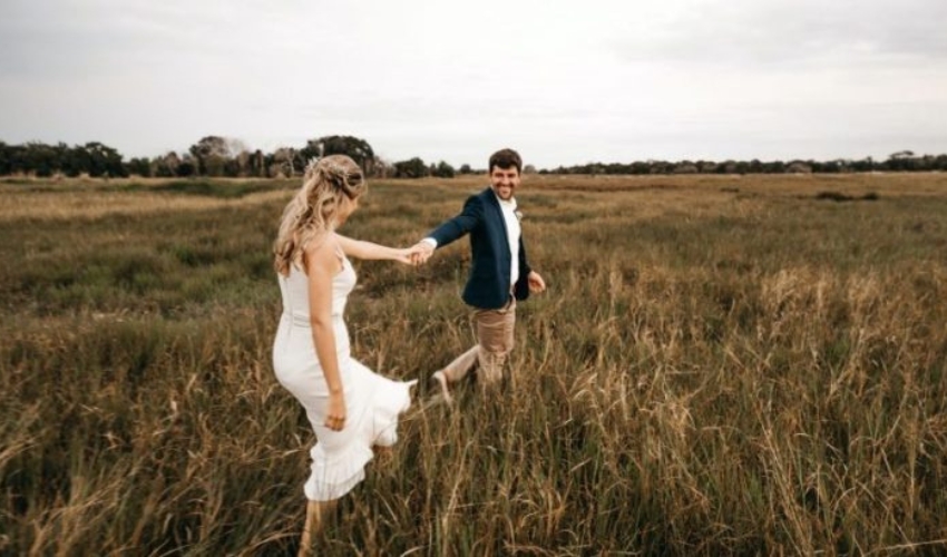 un homme et une femme se tenant la main se promenent dans le champ