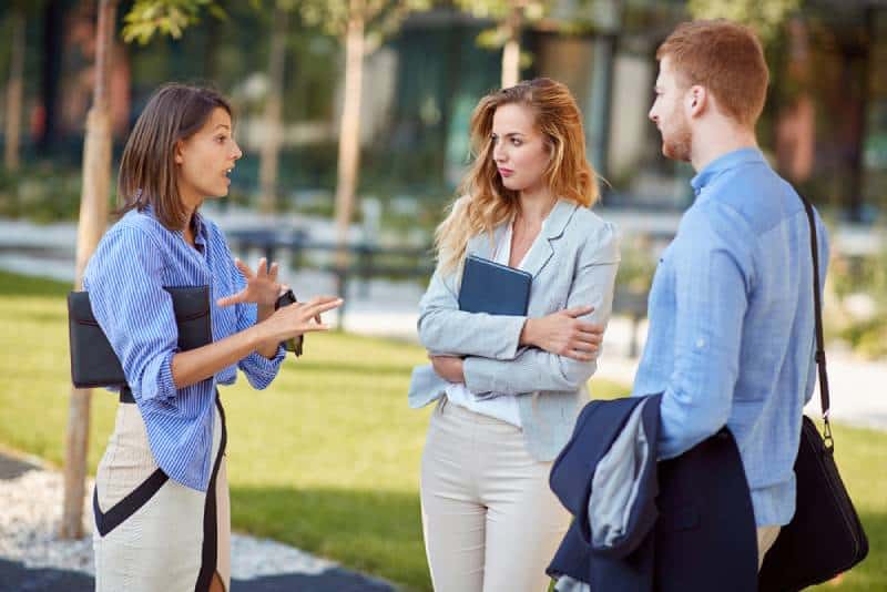 Une femme explique et fait un geste à ses collègues, partenaires commerciaux