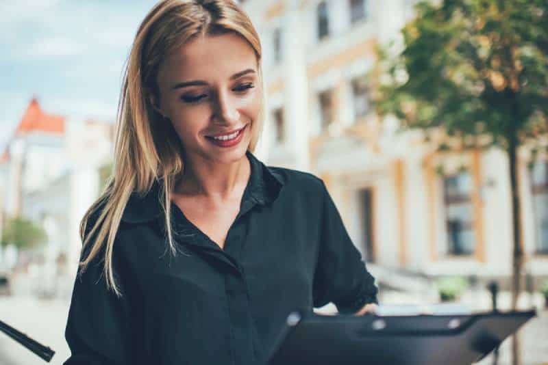 Une femme heureuse en tenue décontractée analyse les informations contenues dans les journaux