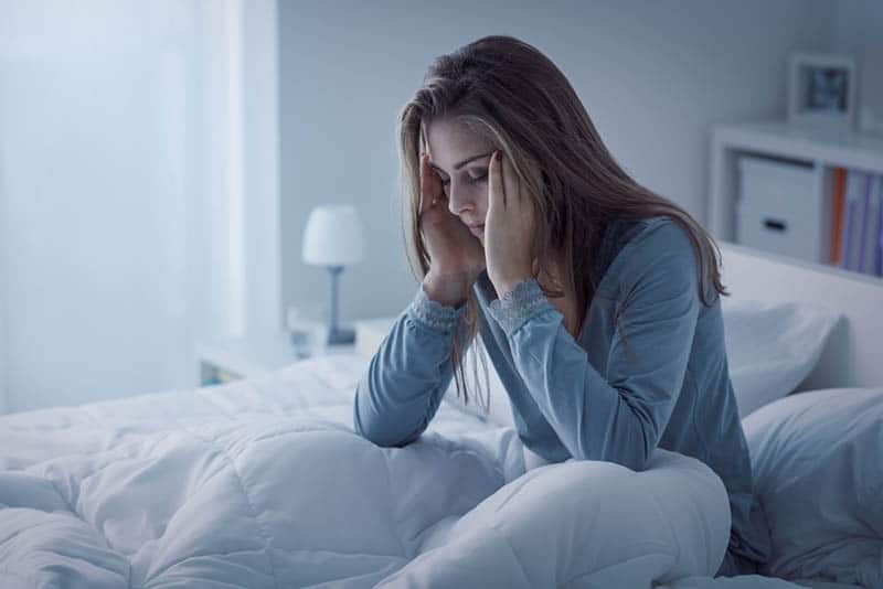 Une femme inquiète, assise sur son lit