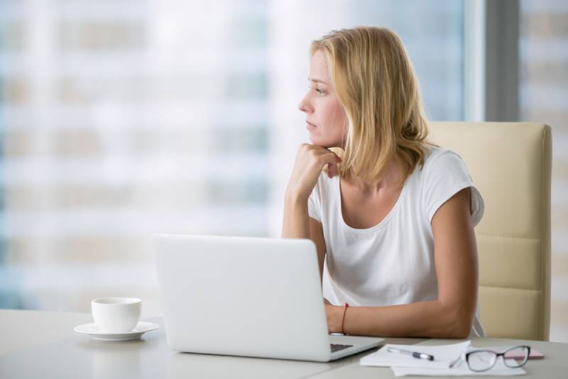 Une femme réfléchie au bureau qui regarde à l'extérieur