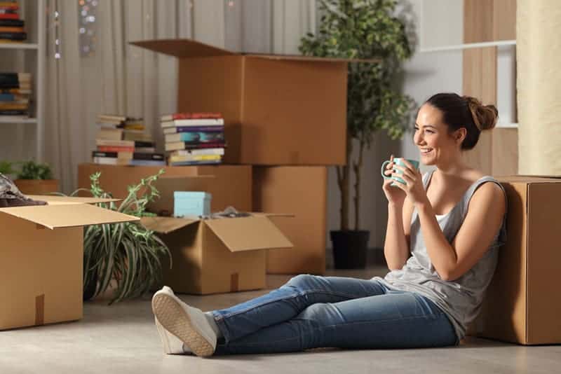 Une femme souriante assise par terre à la maison