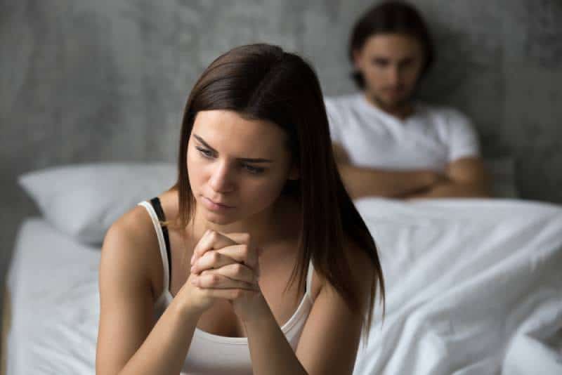 Une fille frustrée est assise sur son lit et pense à un problème relationnel