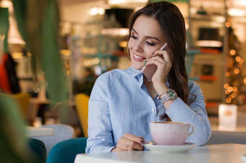 Une fille souriante parle au téléphone dans un café