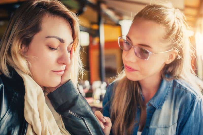 Une jeune femme réconforte une amie triste au restaurant