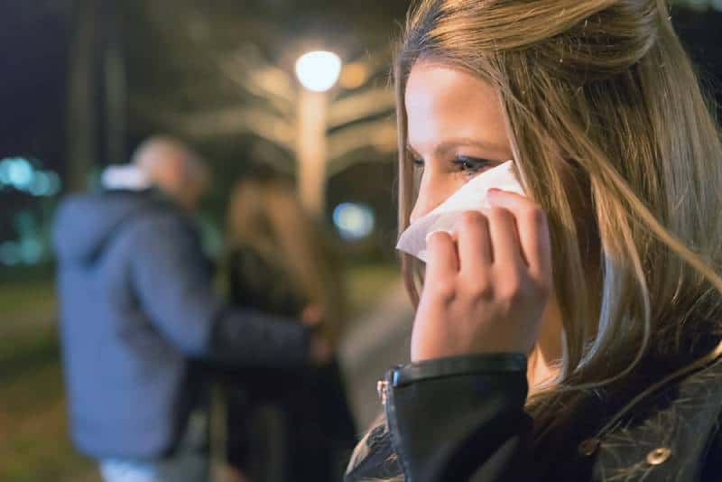 Une jeune fille en pleurs, bouleversée, découvre son petit ami avec une autre femme.