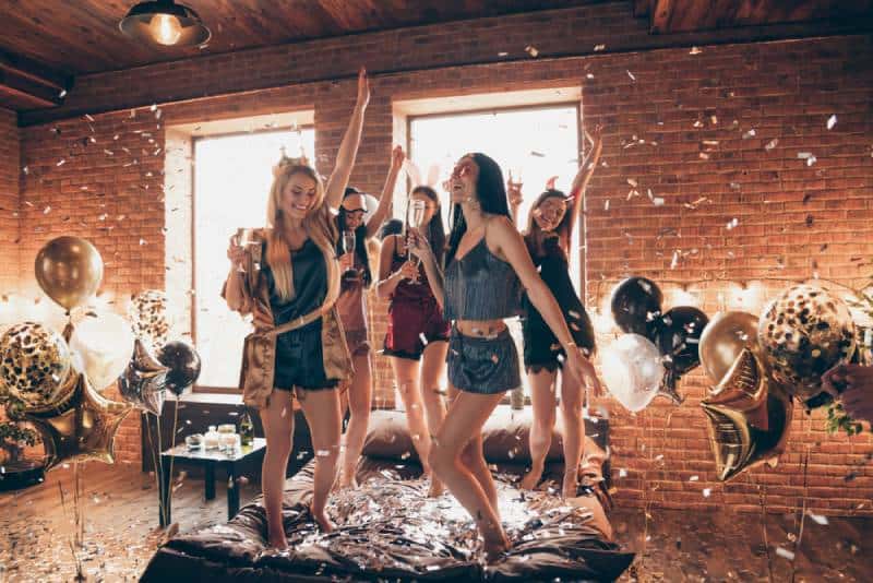 Vue en taille réelle d'un joli groupe de femmes séduisantes et royales s'amusant à danser sur le lit
