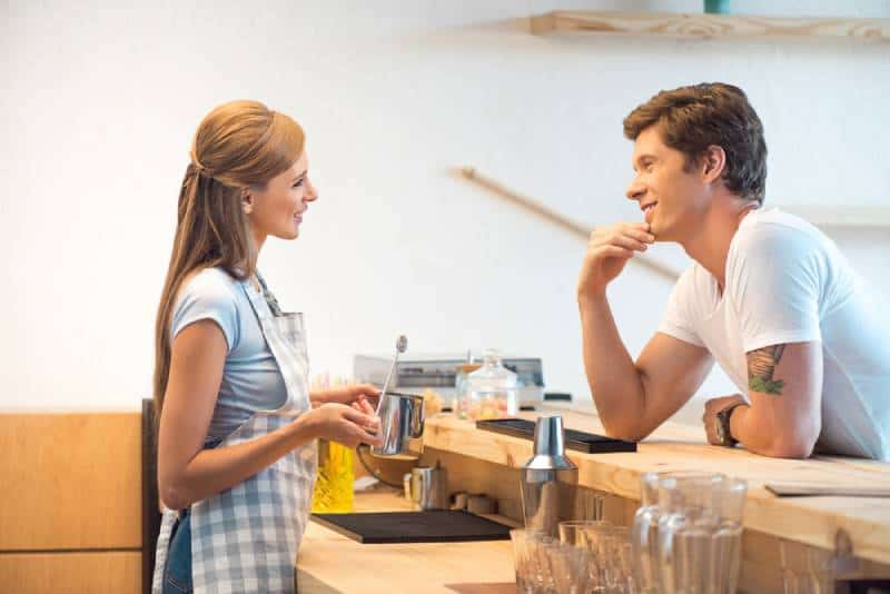 Vue latérale d'un jeune homme et d'une jeune femme flirtant dans un café