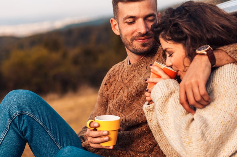 couple en sweat-shirt buvant un café à l'extérieur