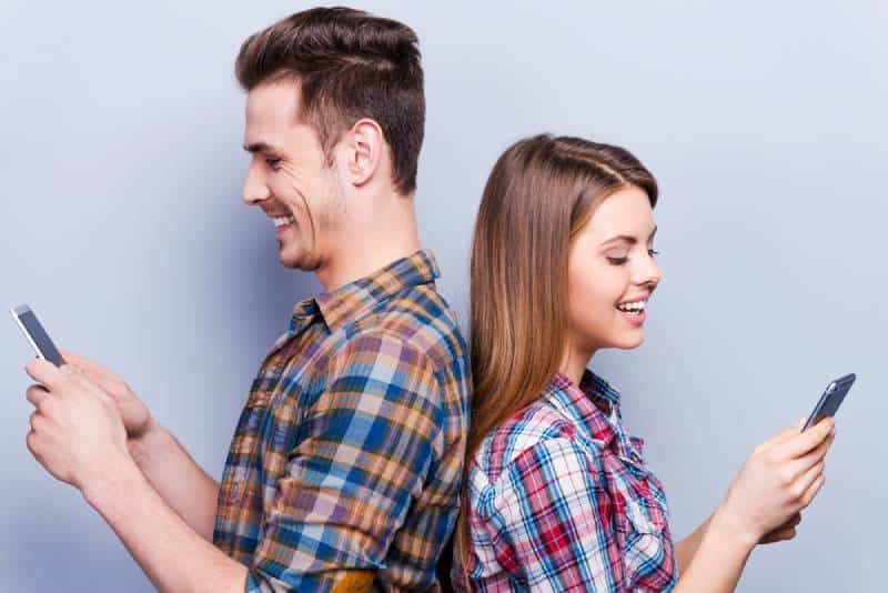 couple se tenant dos à dos et tapant au téléphone