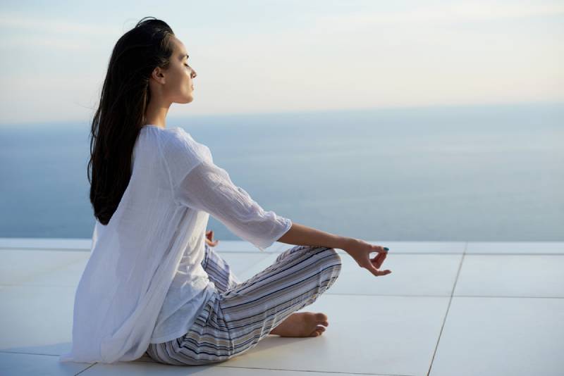 des jeunes femmes pratiquent la méditation yoga au coucher du soleil avec vue sur l'océan en arrière-plan