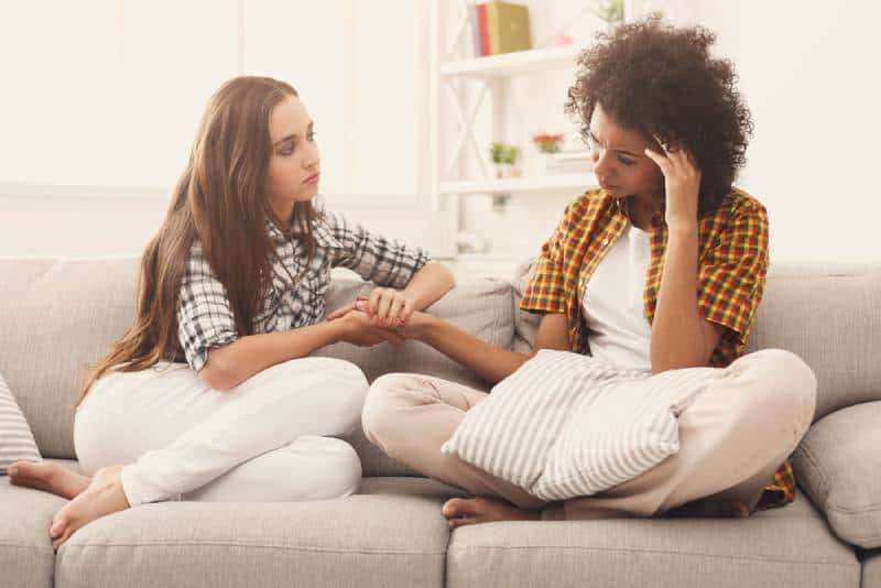 deux femmes parlent de leurs problèmes alors qu'elles sont assises sur un canapé à la maison