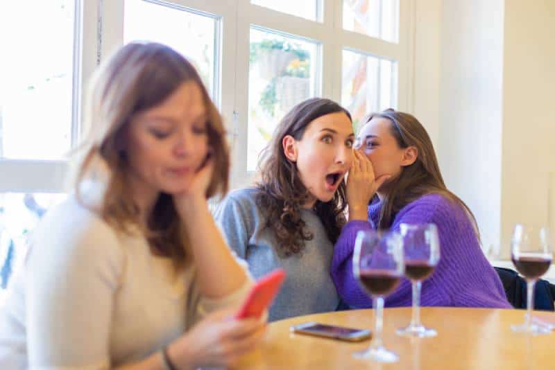 deux filles malveillantes bavardant avec leur amie dans un café