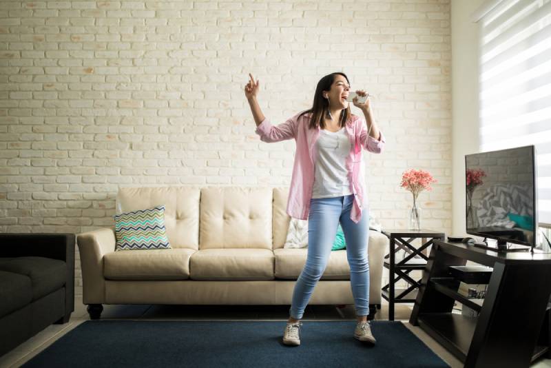 femme chantant au karaoké seule dans son appartement