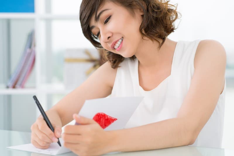 femme heureuse écrit une lettre d'amour