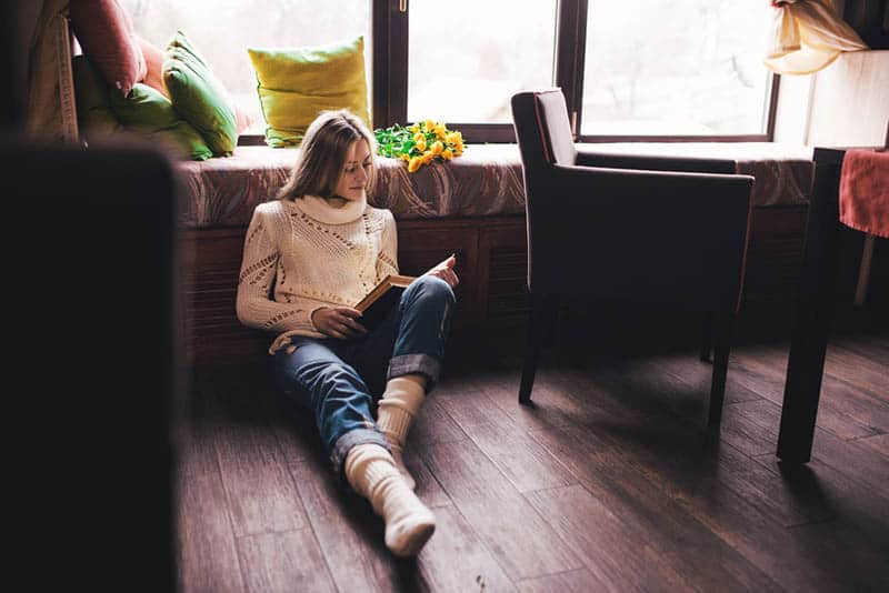 femme lisant un livre en étant assise sur le sol