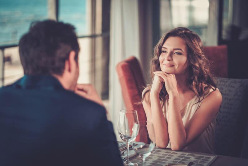 une femme souriante regardant un homme assis à une table devant elle