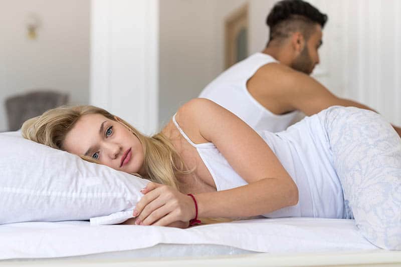 femme réfléchie allongée sur le lit à côté d'un homme