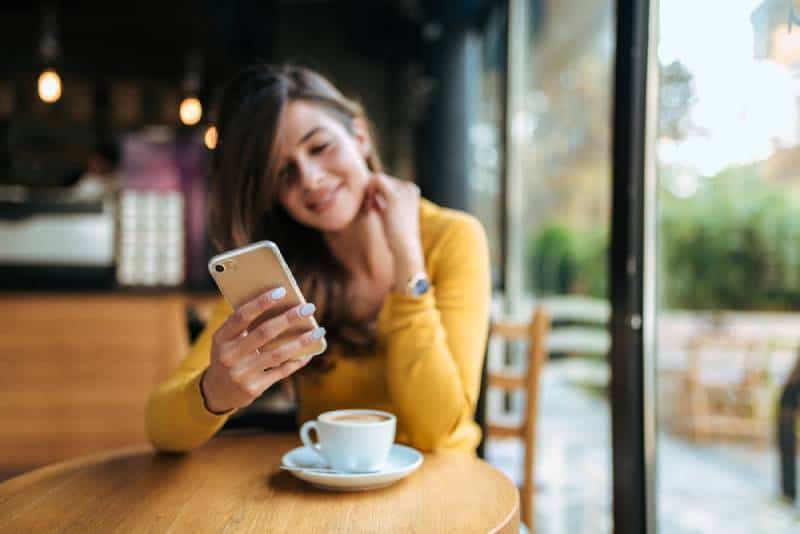 femme tapant sur son téléphone au café