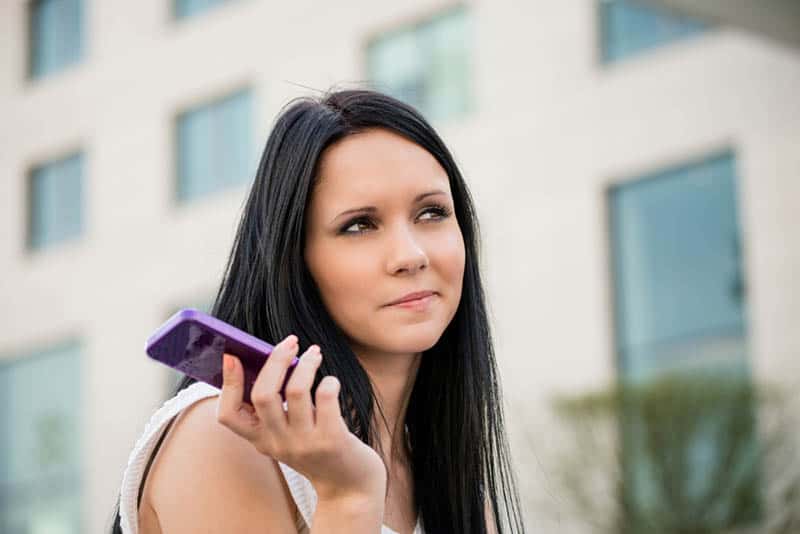 femme tenant un téléphone à l'extérieur