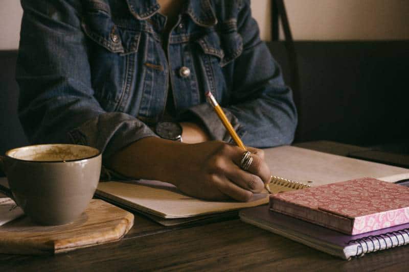 fille écrivant dans un carnet à la maison