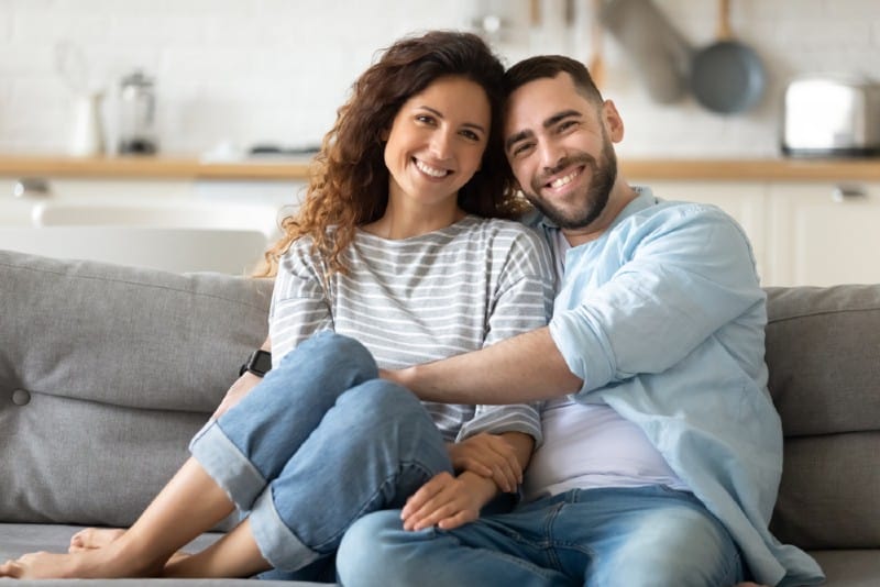 un homme heureux et une femme assise sur le canapé se serrant