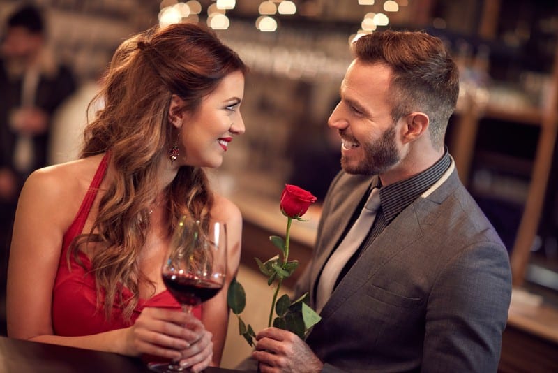 homme offrant une rose rouge à une femme heureuse