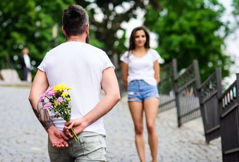 homme tenant des fleurs et attendant sa petite amie