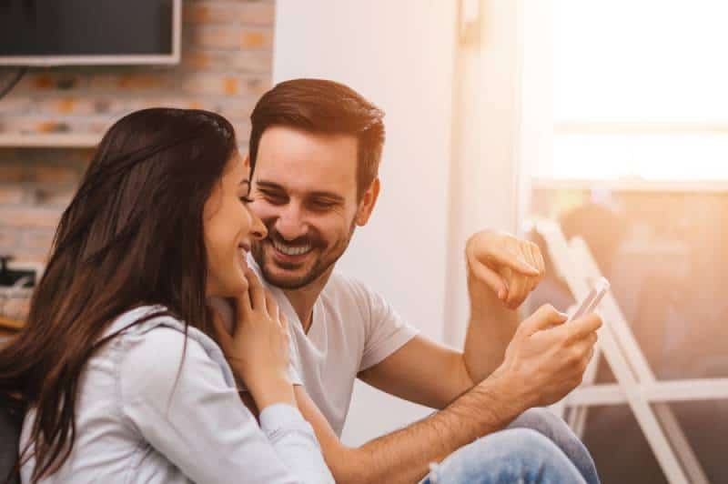 homme tenant le téléphone tout en souriant femme le regardant
