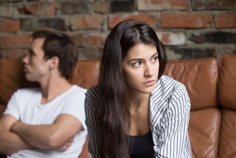 Jeune couple malheureux en colère s'ignorant tout en étant assis sur un canapé