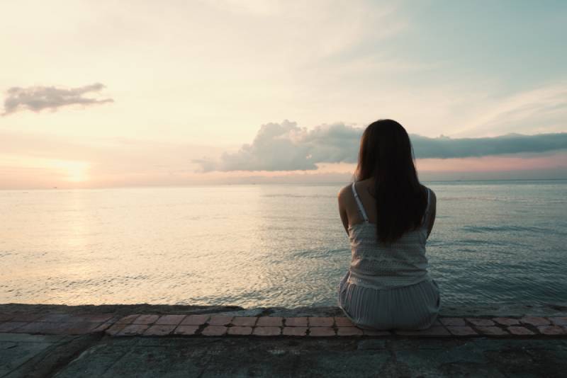 jeune femme assise seule à l'arrière, en plein air, sur la plage d'une île tropicale