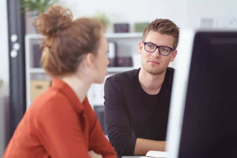 jeune homme d'affaires en réunion écoutant une collègue avec une expression réfléchie